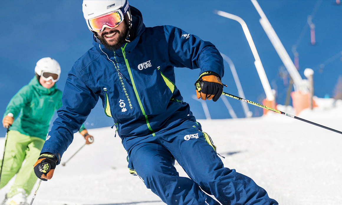 Rasante Abfahrt im Schnee in der Nähe eines Ferienparks im Skigebiet.