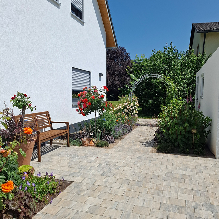 Blühende Beete und eine sauber gepflasterte Einfahrt ergeben ein harmonisches Gesamtbild.