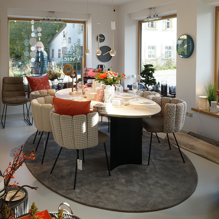 Esstisch Tercio, dessen ovale Tischplatte mit Schweizer Kante in Eiche weiß geölt von zwei filigran geschwungenen Stahlsäulen getragen wird, die flexibel positioniert werden können.