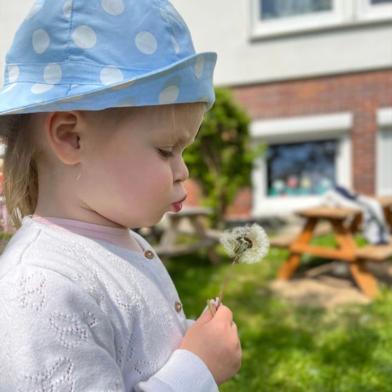 Kleine Momente, die bleiben: In der Pusteblume steht das Kind im Mittelpunkt – mit Zeit, Nähe und einem familiären Umfeld.